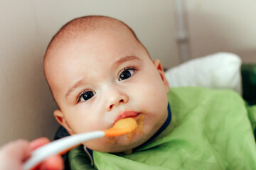 Feeding the baby. Child eating by spoon baby food vegetable puree