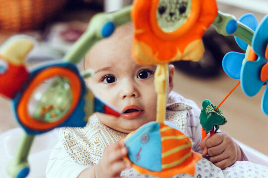 Cute chubby baby playing with colorful toys. Sweet infant at home