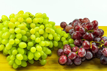 Bunch of red and green fresh grapes on wood and white bacground