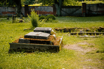 Kuks, East Bohemia, Czech Republic, 10 July 2021: Old grassed graveyard with broken stone...