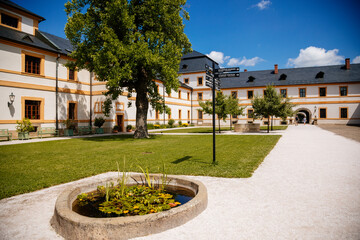 Kuks, East Bohemia, Czech Republic, 10 July 2021: Baroque castle and hospital Kuks, courtyard with garden and antique facade, Beautiful complex with chateau, Holy Trinity Church at sunny summer day.