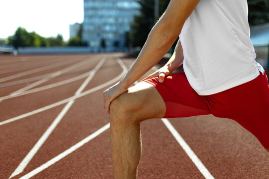 Cropped image of male athlete, runner training at public stadium, sport court or running track outdoors. Summer sport games. Man's legs