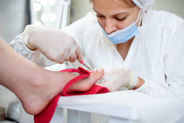 Pedicurist master makes pedicure on woman's legs. Woman giving a professional pedicure at the beauty spa salon. Woman body care. Relaxing, feet spa treatment. Closeup, selective focus