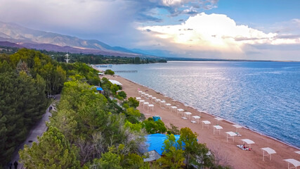 Idyllic summer landscape with lake near mountain with reflection from clouds and forest. Issyk kul,...