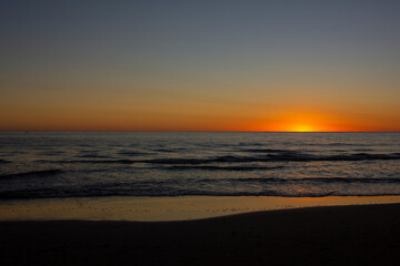 Fototapeta na wymiar El sol se oculta en el horizonte del mar hermoso