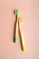 Two yellow and green eco friendly natural bamboo toothbrushes on pink background. Health care, copy space. Zero waste concept.