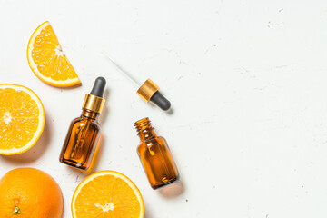 Vitamin C. Fresh citrus fruits with serum bottles at white. Cosmetic products. Flat lay.