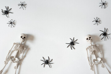 Two toy skeletons with black spiders to celebrate Halloween night. White background with copy space