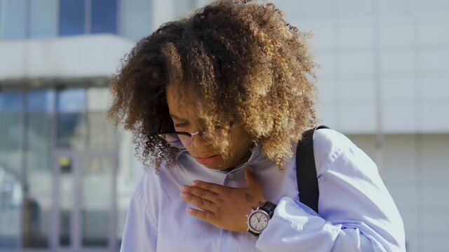 African american businesswoman with curly hair have fit of coughing, outdoor