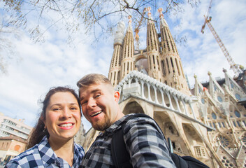 Happy tourists photographing in front of the famous Sagrada Familia roman catholic church in...