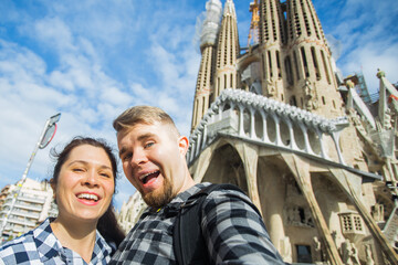 Happy tourists photographing in front of the famous Sagrada Familia roman catholic church in...