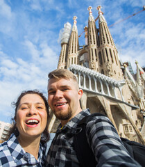 Happy couple making selfie photo in front of the famous Sagrada Familia catholic cathedral. Travel...