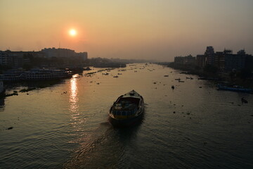 Naklejka premium バングラデシュの首都。 早朝のダッカ。 美しい朝日と川を進むタンカー。