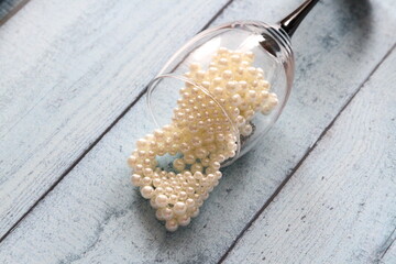 A crystal glass and white pearl beads. Photo of a jewelry demonstration.