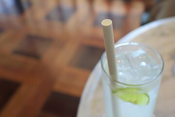 Selective focus of white paper straw on a ice lemon juice glass. Paper straw is good for environment more than plastic straw. Object, drink, and environment concept.