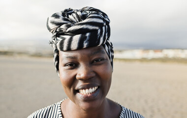 Portrait of happy african woman looking at camera outdoor - Focus on face