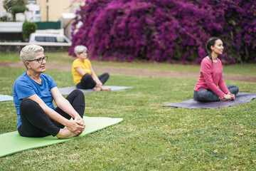 Happy people doing yoga class at city park - Focus on right senior face