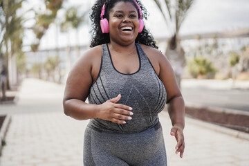 Curvy african woman jogging outdoor at city park - Sport concept - Focus on face