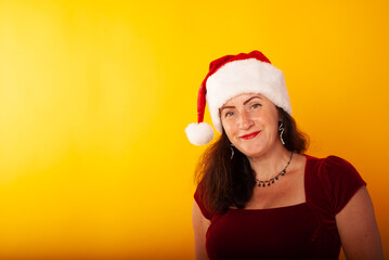 a woman on a yellow background in isolation in a Santa Claus hat in a red dress with a place for tects or your advertising discount in the mall