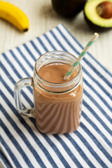 Homemade Chocolate Avocado Smoothie in a Glass Jar Mug, low angle view.