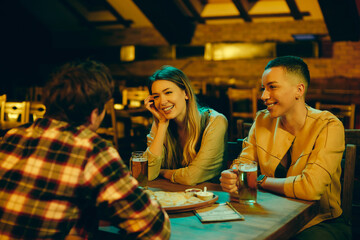 Young happy friends talking while spending the night out in a pub.