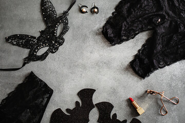 Flat lay composition with black sexy lace face mask and lingerie for Halloween party on grey background, top view from above - obrazy, fototapety, plakaty