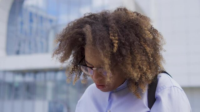 Funny black woman with afro-hair sneezing walking outdoor, seasonal allergy