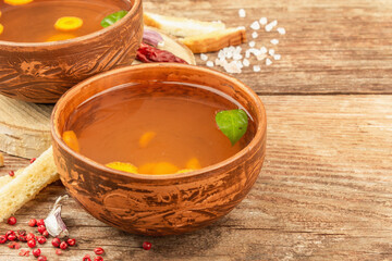 Transparent chicken broth with vegetables in ceramic bowls