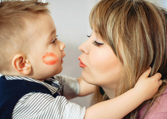 Funny family photo. The one-year-old son hugs his mother tightly and looks at each other. Close-up...