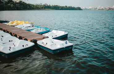 white and blue boats on the pier, catamarans by the water, stationary boats and catamarans at the...
