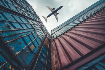 Freight airplane flying above overseas shipping container . Logistics supply chain management and international goods export concept . - obrazy, fototapety, plakaty