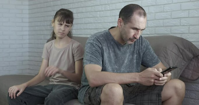 Busy father with telephone. A view of a busy father in smartphone chatting while her daughter want to speak with her.