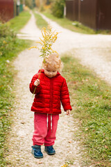 little girl holding a yellow flower on the background of the road