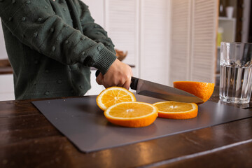 a little girl is sitting at the kitchen table and cutting an orange