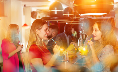 Portrait of smiling young women drinking cocktails and talking on party