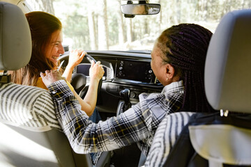 Positive diverse travelers driving car in nature