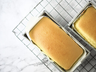 Top view chiffon cake in loaf baking tin on white marble table