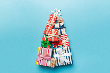 Christmas tree made of beautifuly wrapped presents on colored background, view from above. New Year gift box minimal concept with copy space