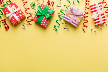 Holiday flat lay with gift boxes wrapped in colorful paper and tied decorated with confetti on colored background. Christmas, Birthday, Valentine and sale concept, top view