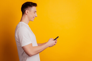 Profile portrait of smart cool guy hold telephone look screen on yellow background
