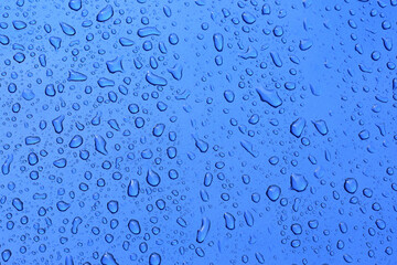 Pattern of raindrops on vivid blue metal surface with grain effect.