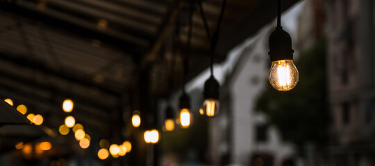 Illumination of the street terrace of a cafe or restaurant. Light bulbs. Cloudy weather.