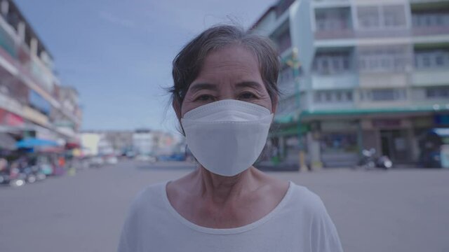 Healthy concept of 4k Resolution. An old woman smiling and giving a thumbs up wearing a mask with a city background.