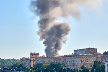 Large clouds of dark smoke over the rooftops of residential buildings. A strong fire in Moscow, a warehouse with pyrotechnics is burning.