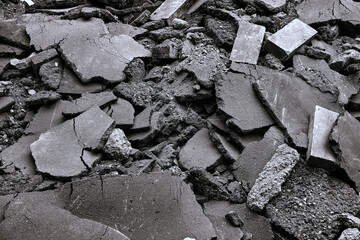 A pile of dark broken asphalt, stones. bricks after collapse building.