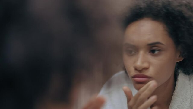 Unhappy woman looking in mirror in the morning, dull skin, lack of vitamins