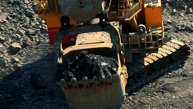 Excavator bucket in a quarry close-up. An excavator loads soil into a mining dump truck. Equipment for the extraction of iron ore in a quarry