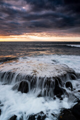 Sunset landscape at the beach with sea ocean and waves in background - dramatic sky with sun and clouds - dusk light and horizon