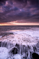 Sonnenuntergangslandschaft am Strand mit Meer, Ozean und Wellen im Hintergrund - dramatischer Himmel mit Sonne und Wolken - Dämmerungslicht und Horizont