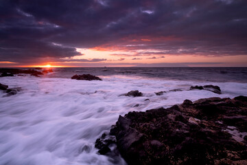Sunset landscape at the beach with sea ocean and waves in background - dramatic sky with sun and...
